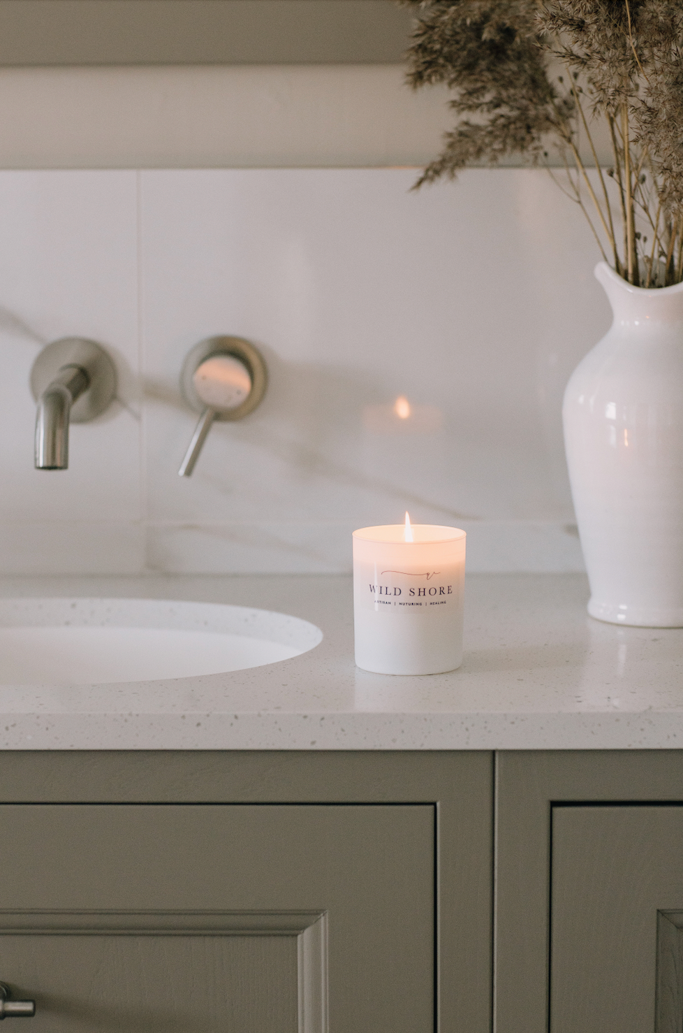 Wild Shore Soy Candle. Frosted matt white branded glass jar. Displayed on a vanity unit in a luxury Bathroom 2